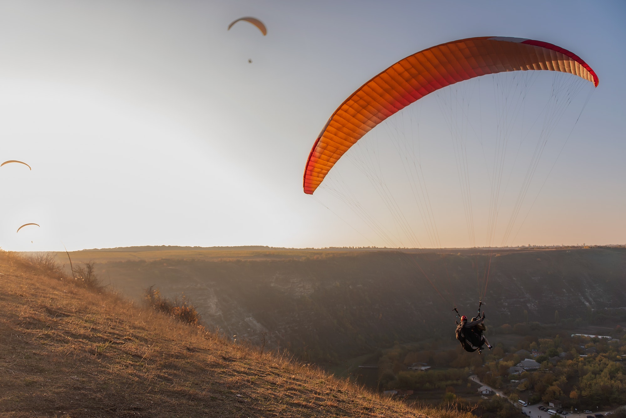 at-sunrise-in-the-blue-sky-paragliders-fly-in-the-rays-of-the-golden-sun